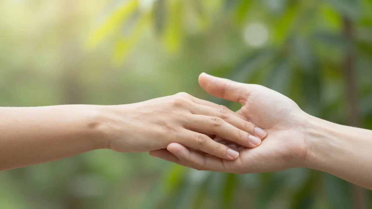 Detail dvou rukou v jemném dotyku, symbolizující obnovené spojení a důvěru.